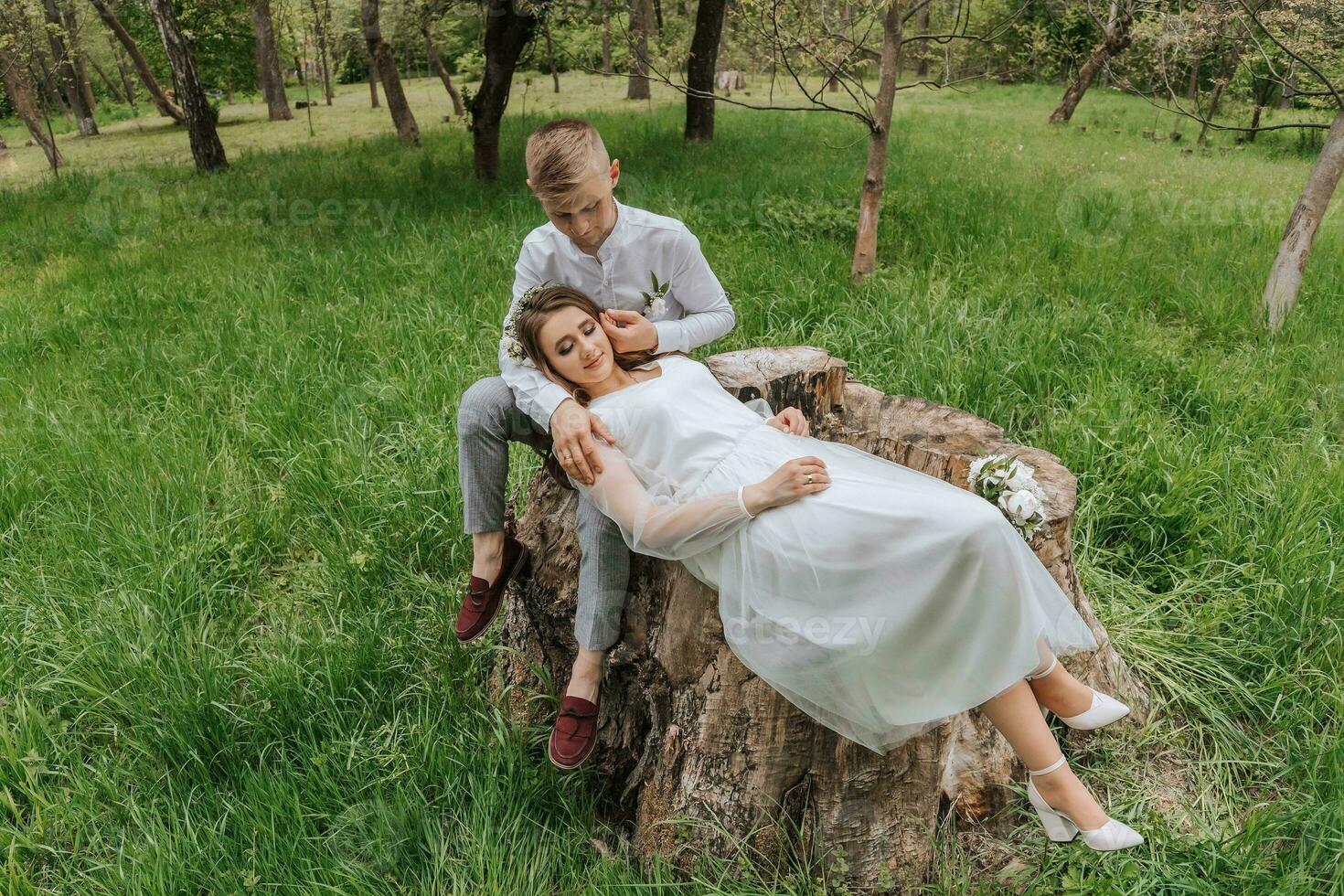 Young couple in the forest. Wedding walk. The bride lies on the lap of the groom photo