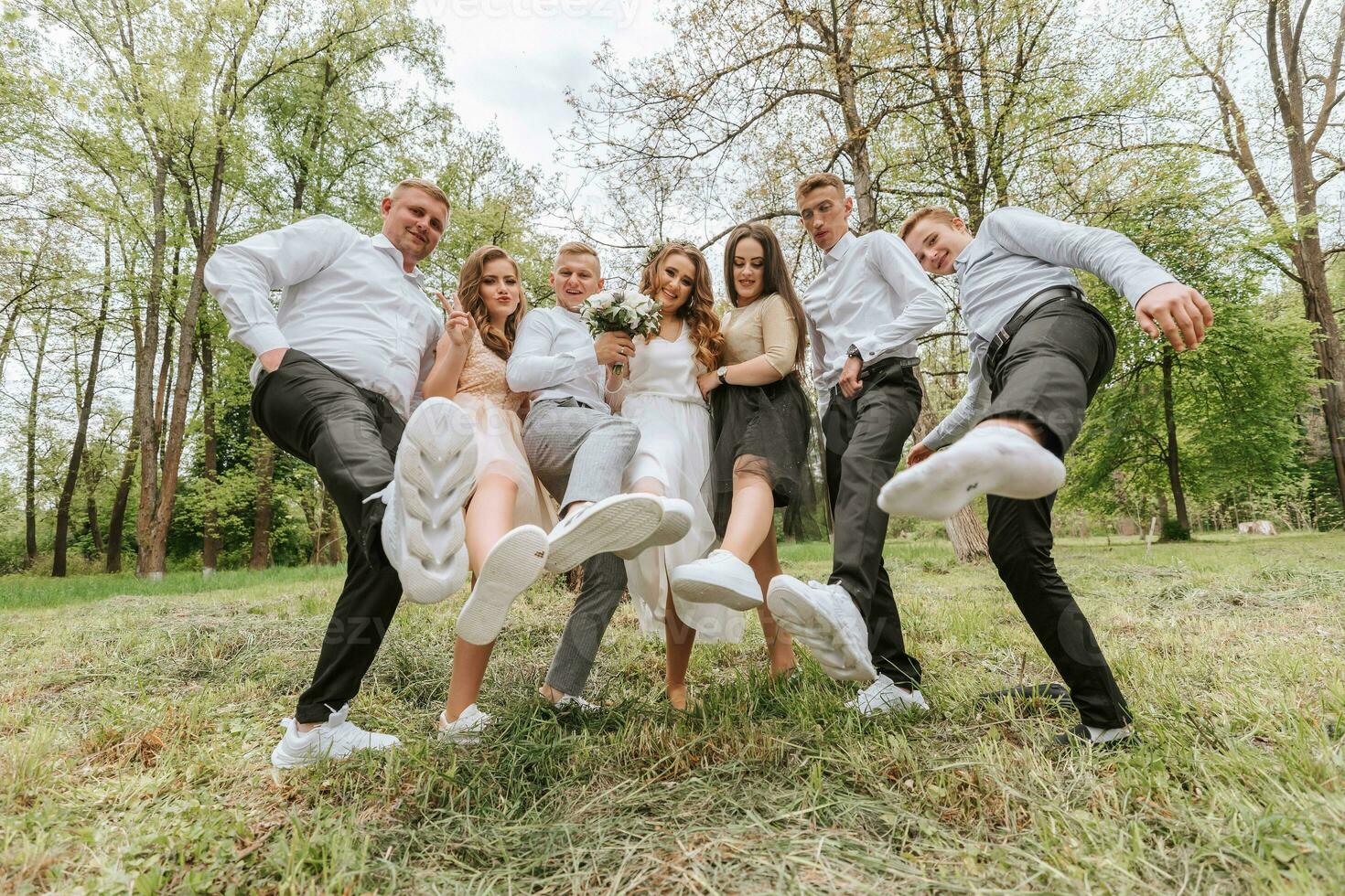 Boda caminar en el bosque. novias y su amigos actitud en contra el antecedentes de el bosque. un grande grupo de personas son teniendo divertido a su amigos' Boda foto