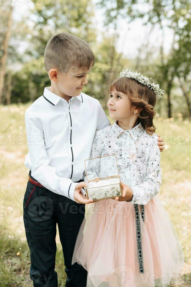 Two children, dressed festively, present wedding rings for brides photo