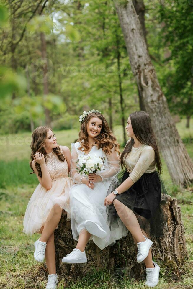 Wedding walk in the forest. Brides and their friends pose against the background of the forest. A large group of people are having fun at their friends' wedding photo