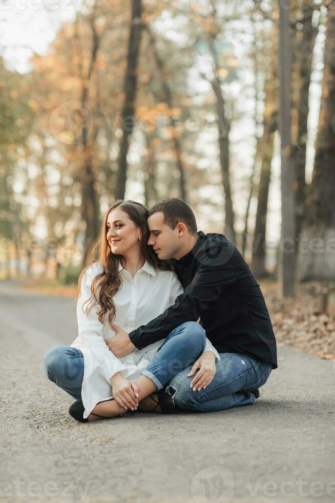 un hombre cerca su embarazada esposa, descansando en un otoño parque. apoyo de el marido durante el embarazo. el tema de mental salud durante el embarazo foto