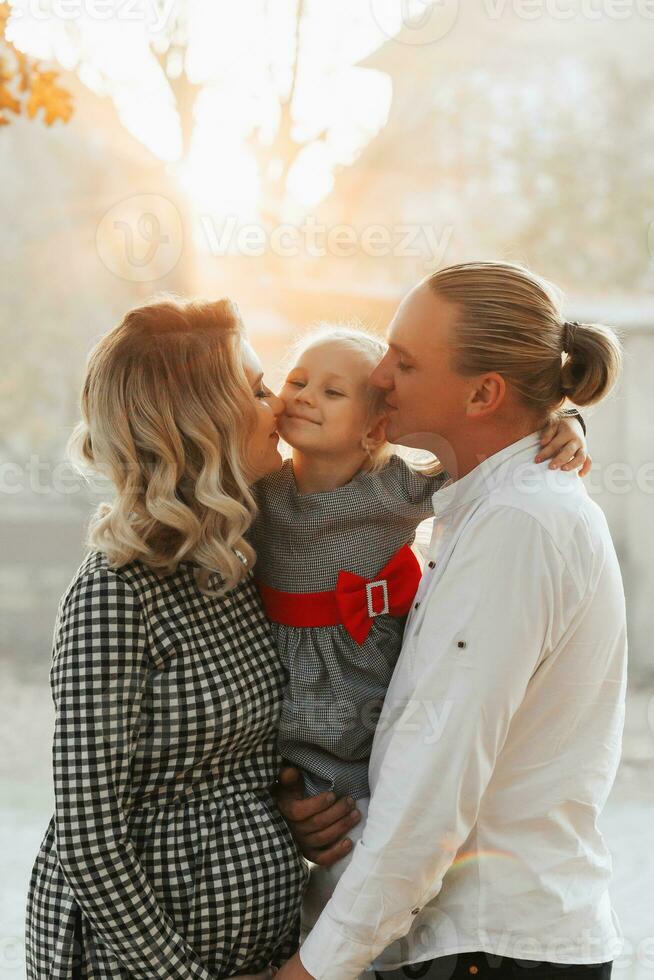 Young pregnant woman with family at sunset in the park photo