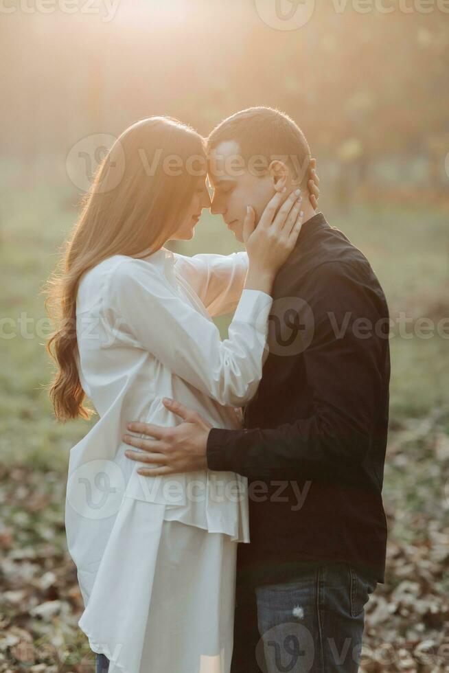 A man near his pregnant wife, resting in an autumn park. Support of the husband during pregnancy. The topic of mental health during pregnancy photo