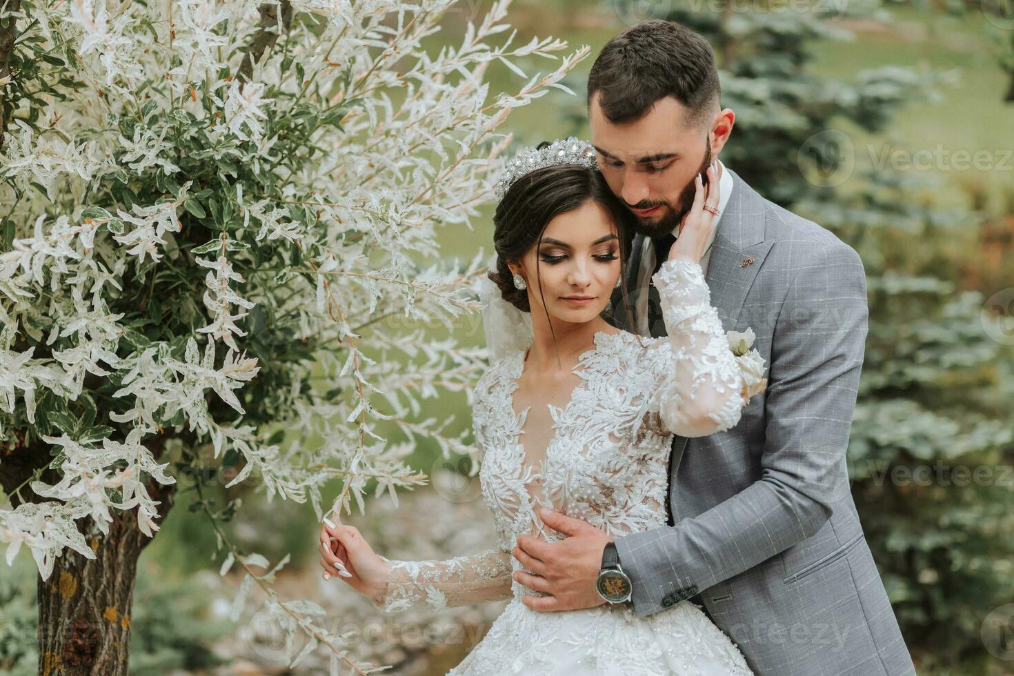 European wedding couple in the park near the stairs. The bride in a beautiful dress with a long train and sleeves. Groom in a classic suit photo