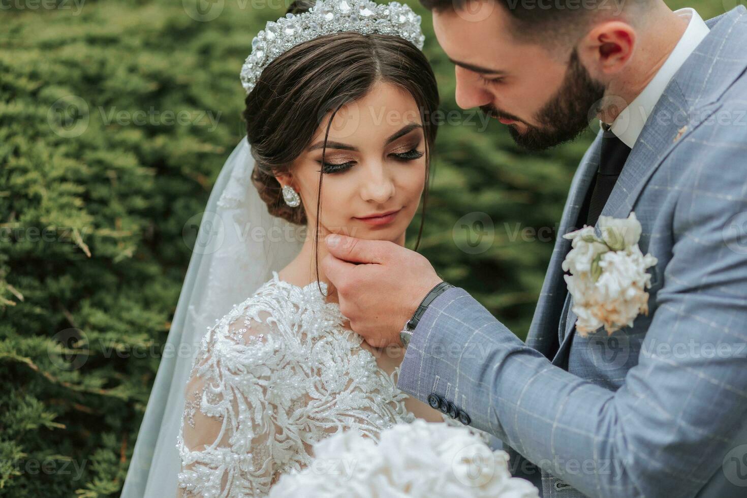 European wedding couple in the park. The bride in a beautiful dress with sleeves and a crown on her head. Groom with a black beard of Caucasian appearance in a classic suit photo