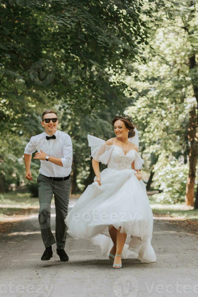 A wedding couple, a happy bride and groom are running in the park to the place of the wedding ceremony. Wedding concept photo