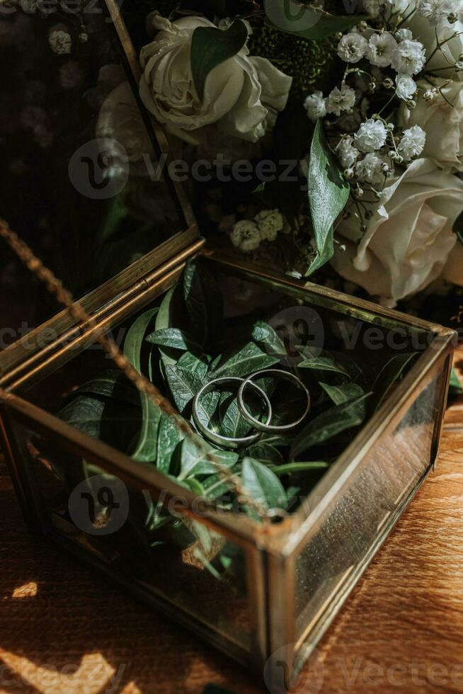 Original wedding rings in gold and glass box on wooden floor in nice light photo