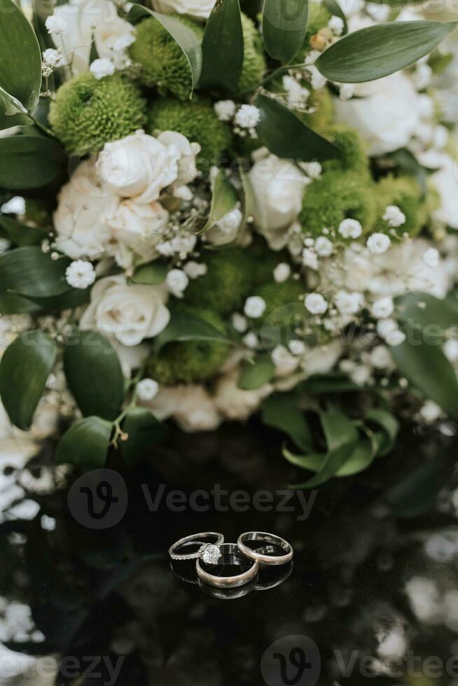 wedding bouquet in a green style of different flowers on a black background, in the foreground of a wedding ring photo