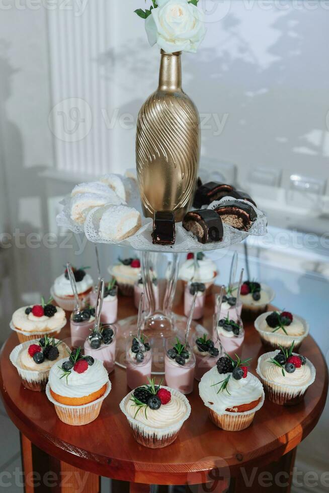 Festive dessert table with sweets. Wedding candy bar, various cakes, chocolates on stands. photo