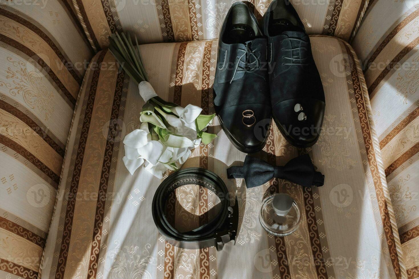 detalles de el novio en el silla. negro terciopelo botas, oro Boda anillos, de los hombres perfume, gemelos, un ramo de flores de calla flores foto