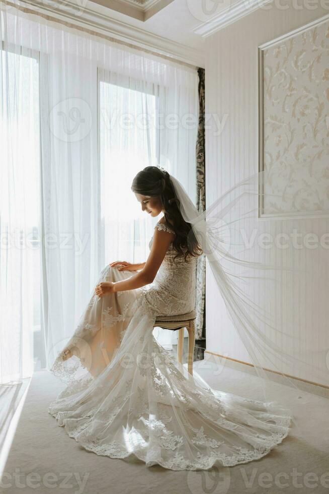 retrato de un hermosa novia en un hotel en contra el antecedentes de un grande ventana foto