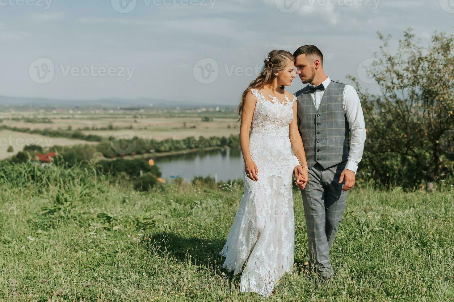 stylish bride and groom hug and kiss against the background of summer mountains. the concept of a rustic wedding in the mountains, happy bohemian newlyweds. photo