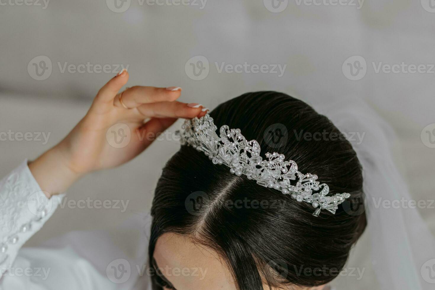 A beautiful bride girl in a white robe, veil and tiara on her head, the sun shines on her from the window. Happy young girl under the glare of sunlight. wedding concept photo