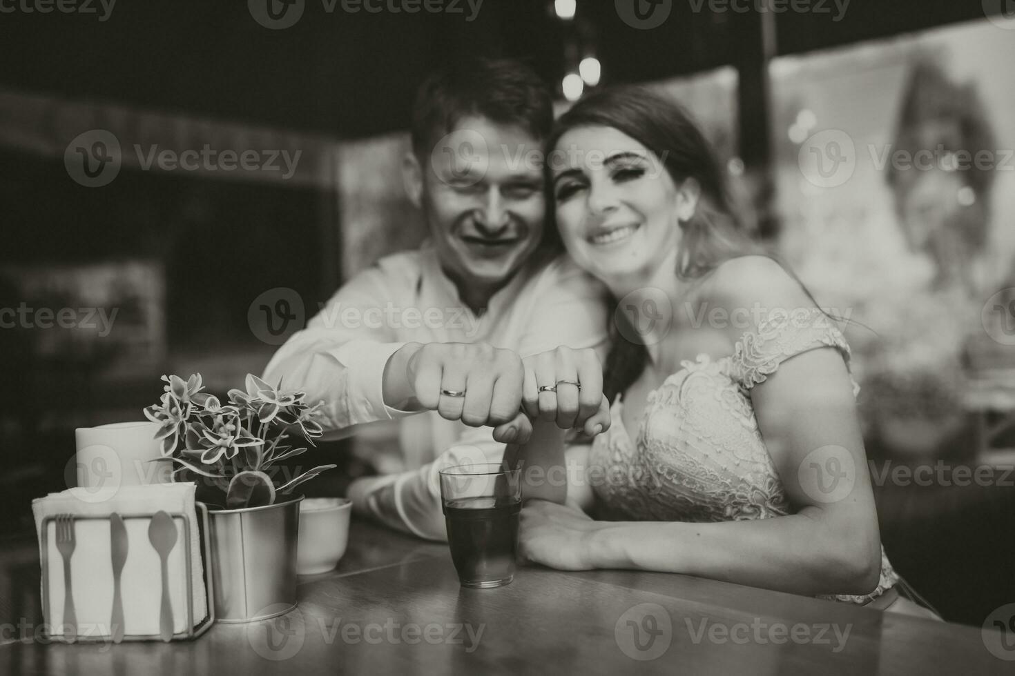 Side view portrait of a loving European couple laughing while enjoying a date in a cafe. Black and white photo