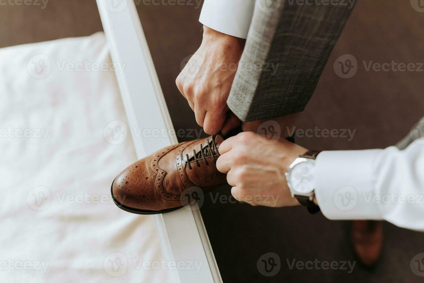 Fashion for men. Close-up of a man tie the shoelaces of his brown leather shoes. A businessman is preparing for a meeting photo