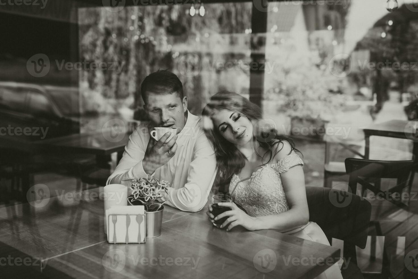 lado ver retrato de un amoroso europeo Pareja riendo mientras disfrutando un fecha en un cafetería. negro y blanco foto