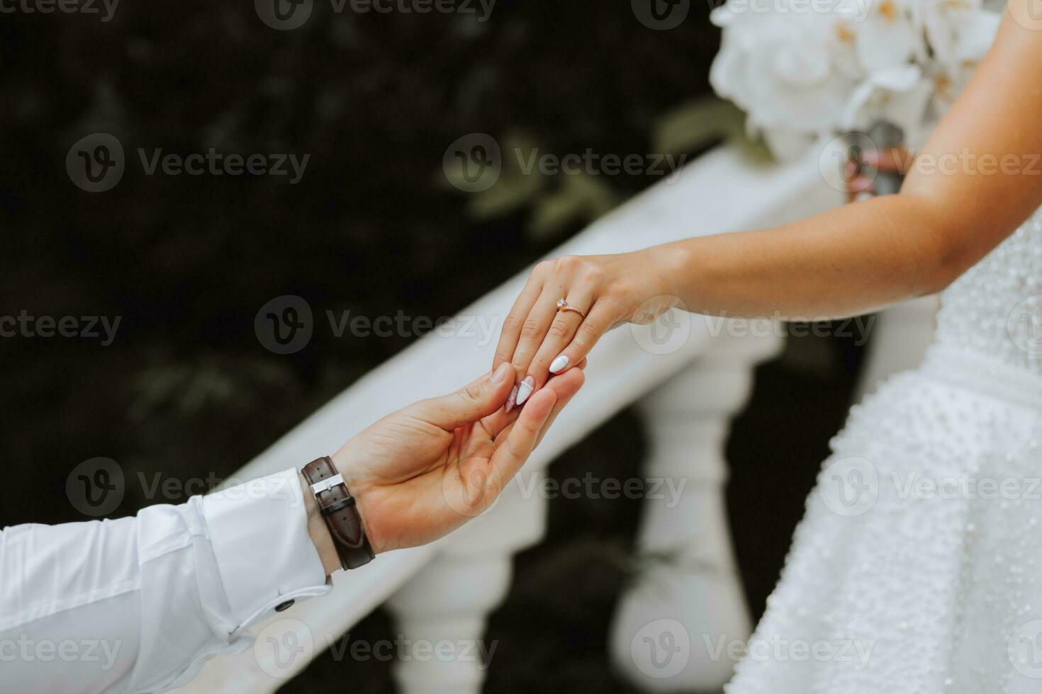 Hands of the bride and groom close-up. The groom holds the bride's hand photo