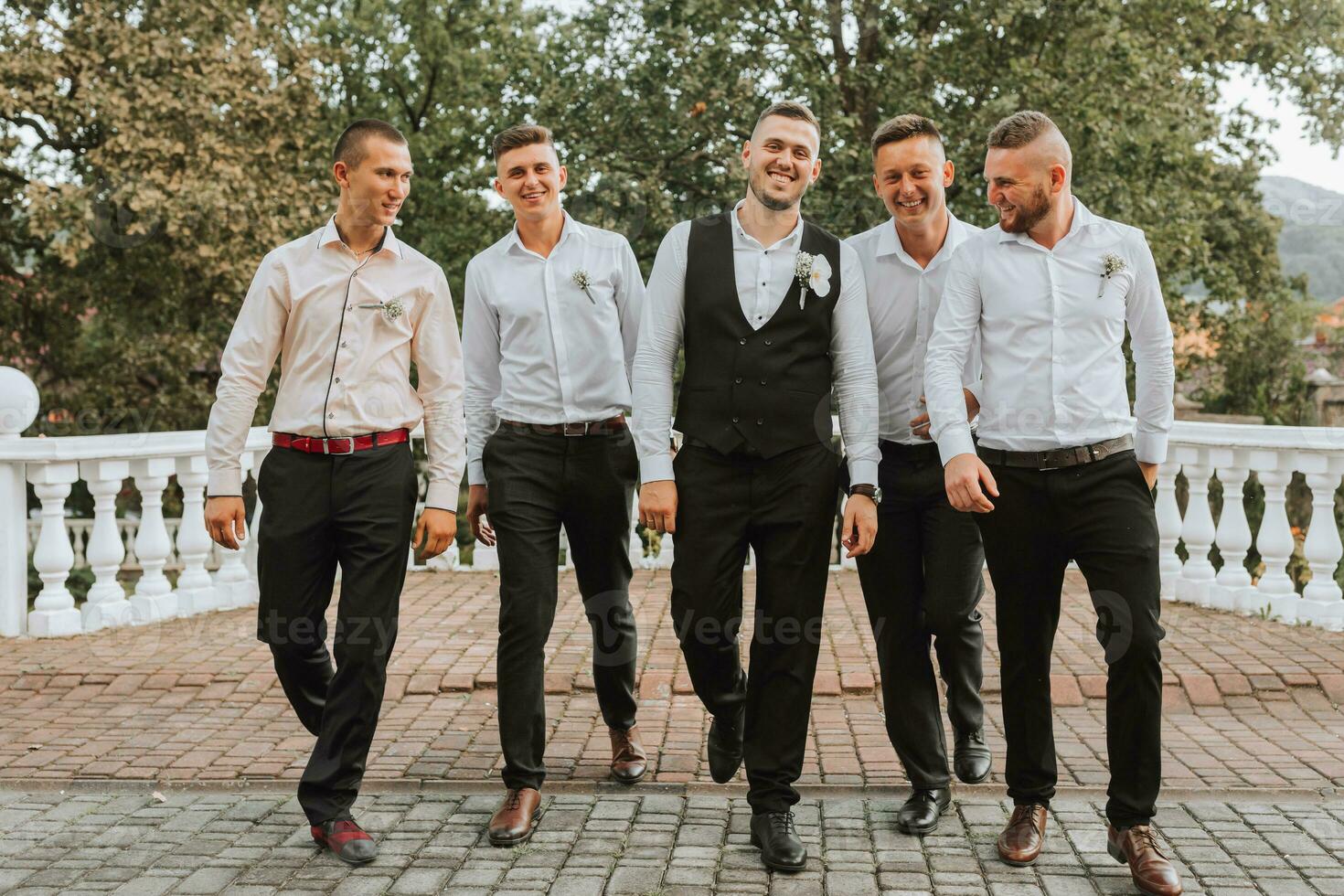 Cheerful, young, energetic groom's witnesses in white shirts next to the groom. Friends congratulate the groom. photo