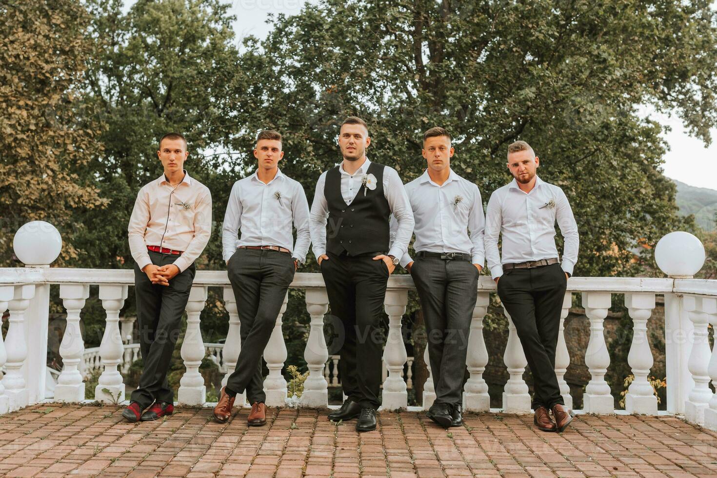 Cheerful, young, energetic groom's witnesses in white shirts next to the groom. Friends congratulate the groom. photo