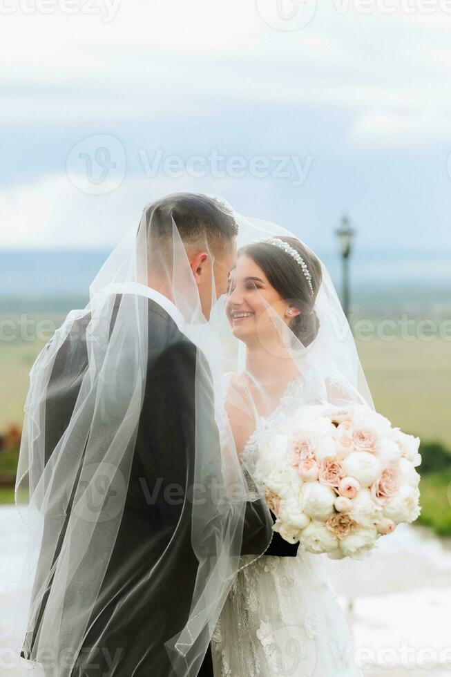 Boda Pareja en naturaleza. novia y novio abrazando debajo el velo a boda. foto