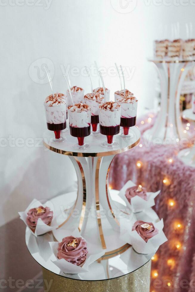 Festive dessert table with sweets. Wedding candy bar, various cakes, chocolates on stands. photo