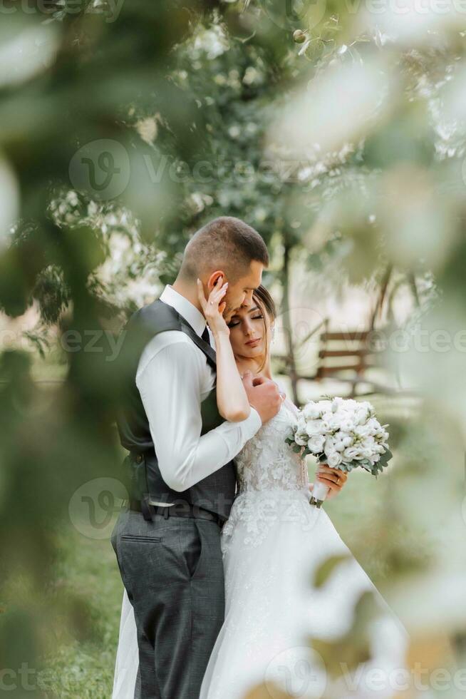 un hermosa boda, un hermosa Pareja en amar, riendo y besos en contra el antecedentes de un verde jardín. alto calidad foto