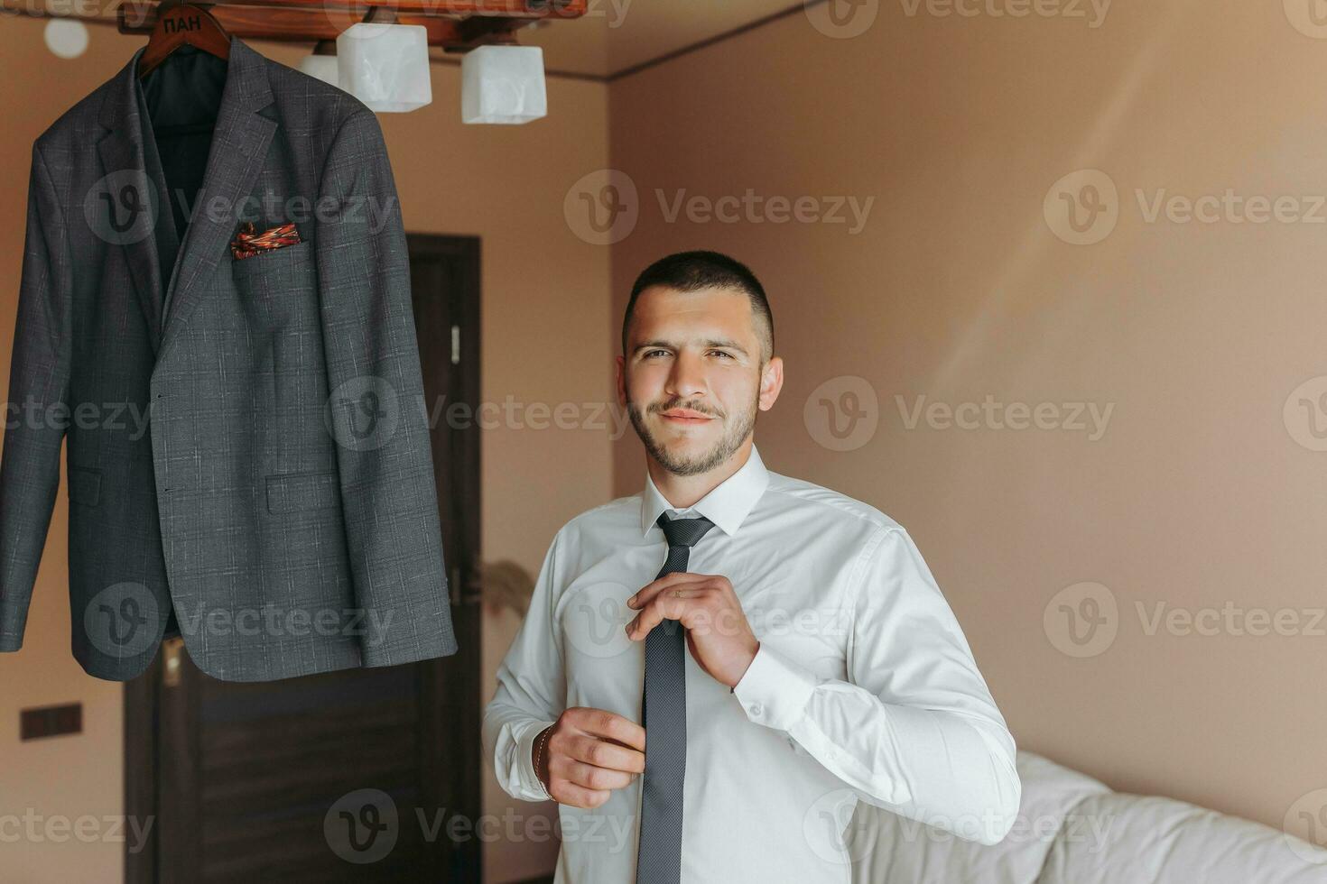 el novio pone en un Corbata antes de poniendo en formal ropa. traje de el novio foto