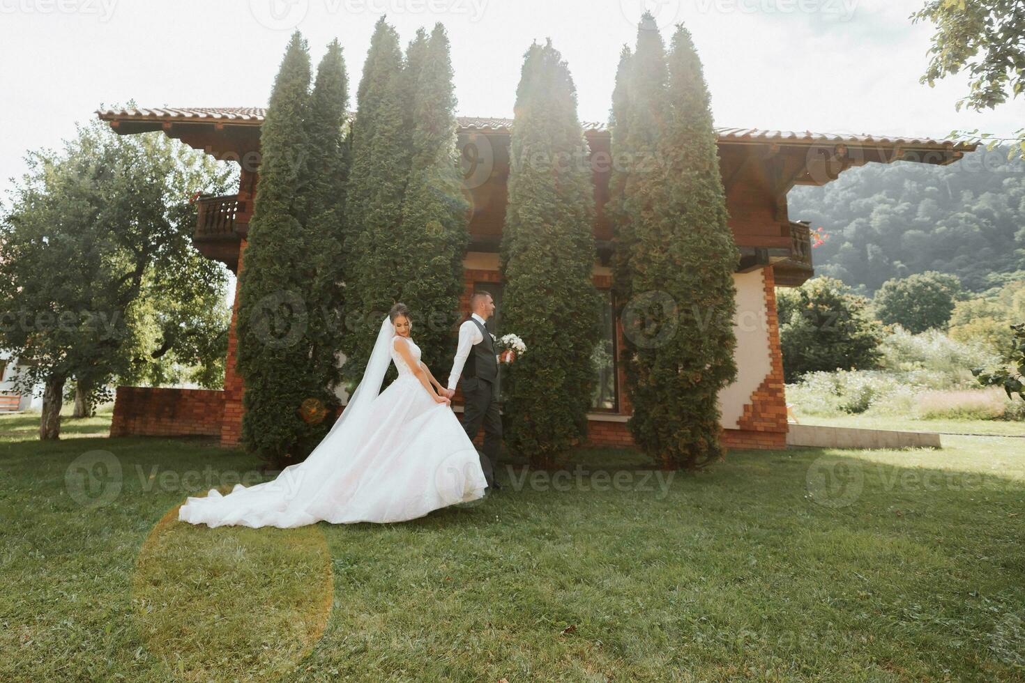 A beautiful wedding, a beautiful couple in love, walking on the background of a green garden with tall green thuja trees. High quality photo