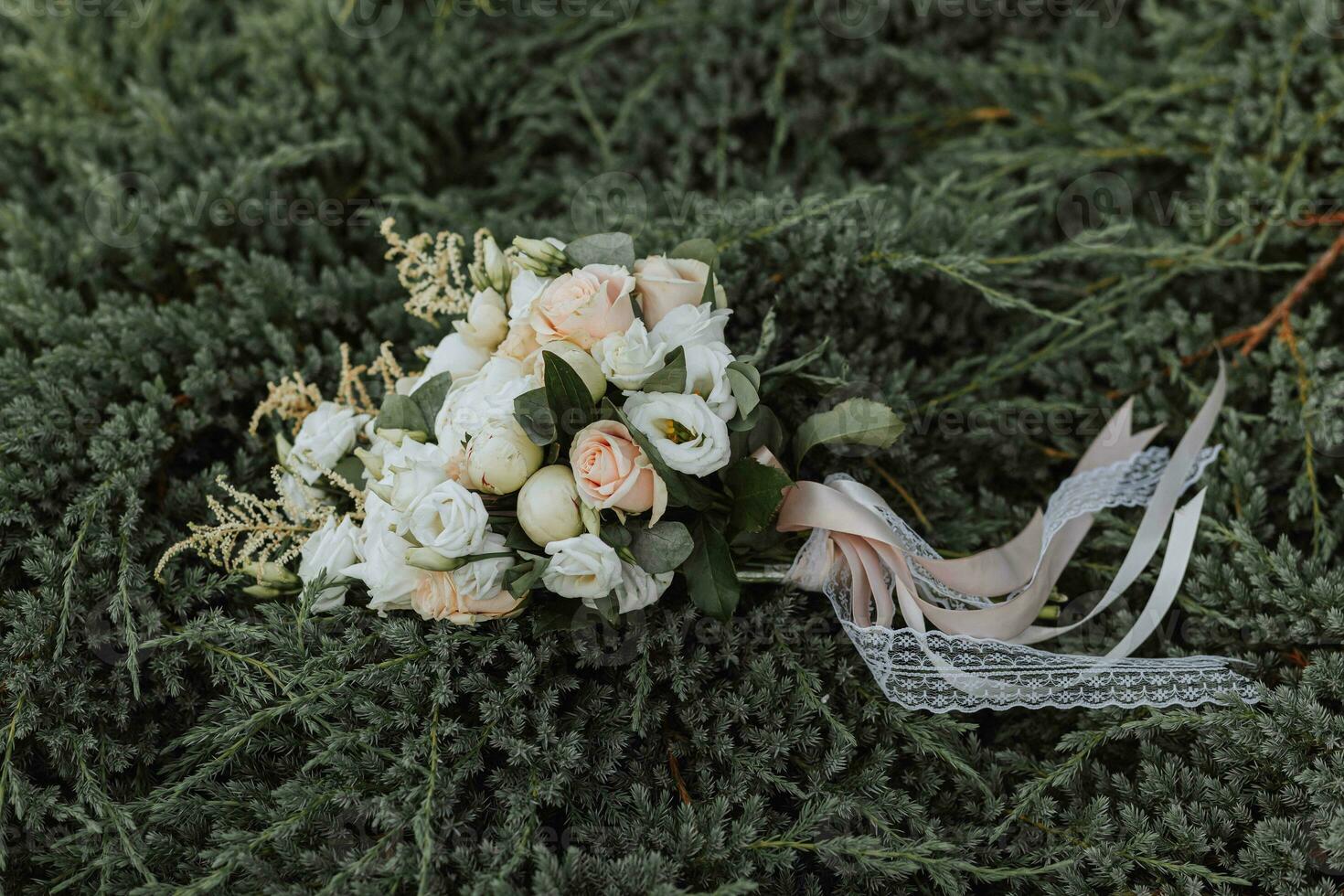 Wedding bouquet of white roses and peonies on green grass. Green background. Close-up photo of the bouquet