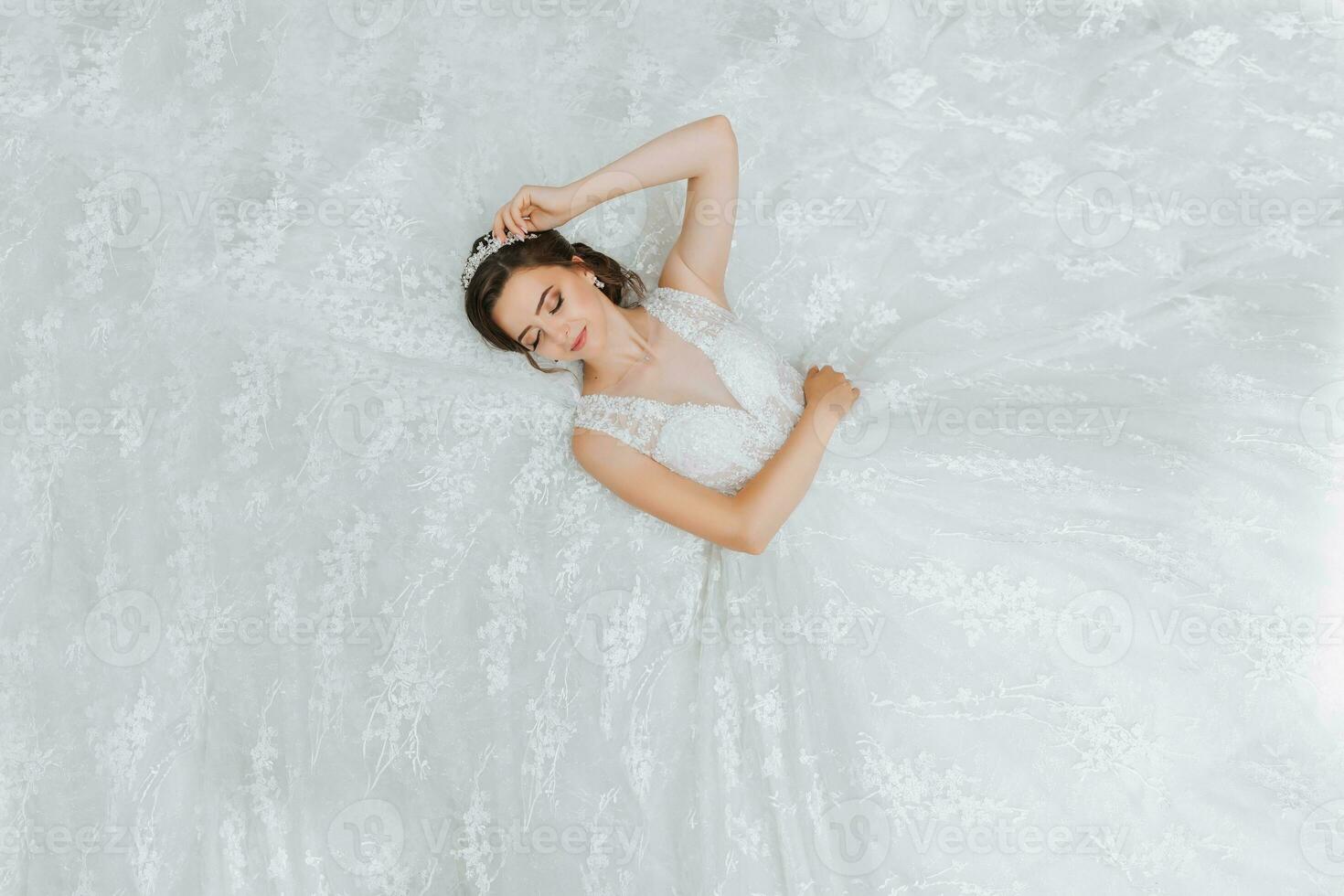 young beautiful bride in wedding dress, lying down, fashion shot under studio light. The photo is taken from above