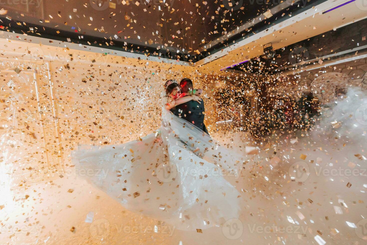 maravilloso novia y elegante novio bailando debajo dorado papel picado a Boda recepción. contento Boda Pareja ejecutando primero danza en restaurante. romántico momentos foto