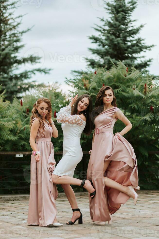 Three young beautiful smiling girls in fashionable clothes. Sexy carefree women posing on the street. Positive models have fun outdoors on green background. Cheerful and happy photo