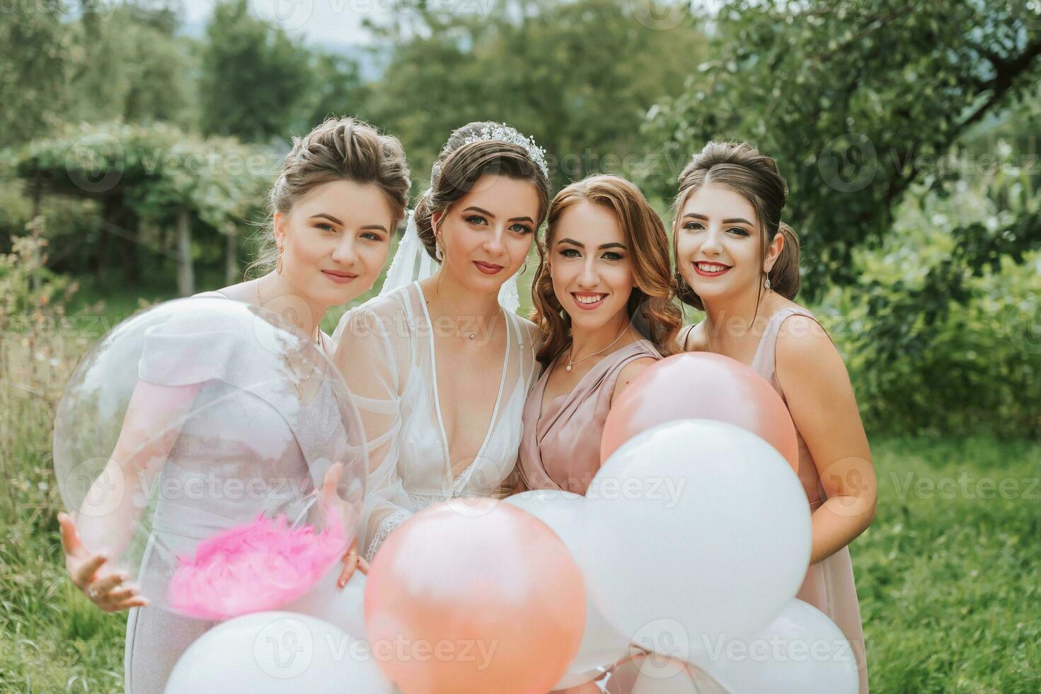 el damas de honor Mira a el sonriente novia. el novia y su divertido amigos celebrar un despedida de soltera fiesta al aire libre en pareo vestidos. el novia y amigos en el césped debajo el abierto cielo foto