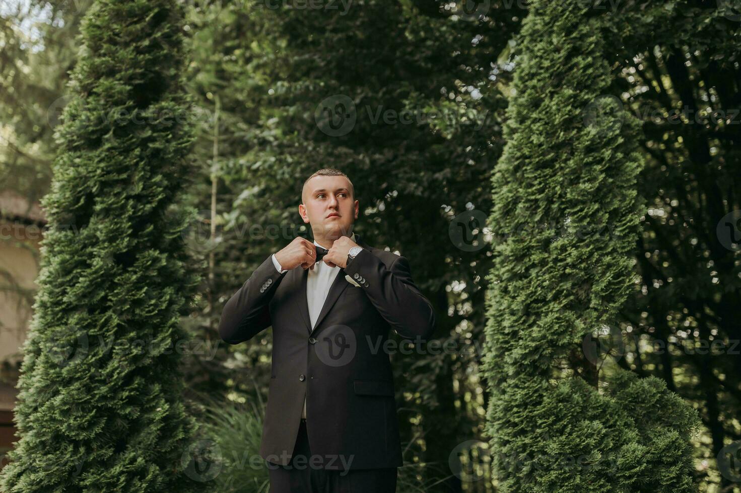 portrait of the groom in a classic suit against a background of green trees. A young man. Style. Fashion photo