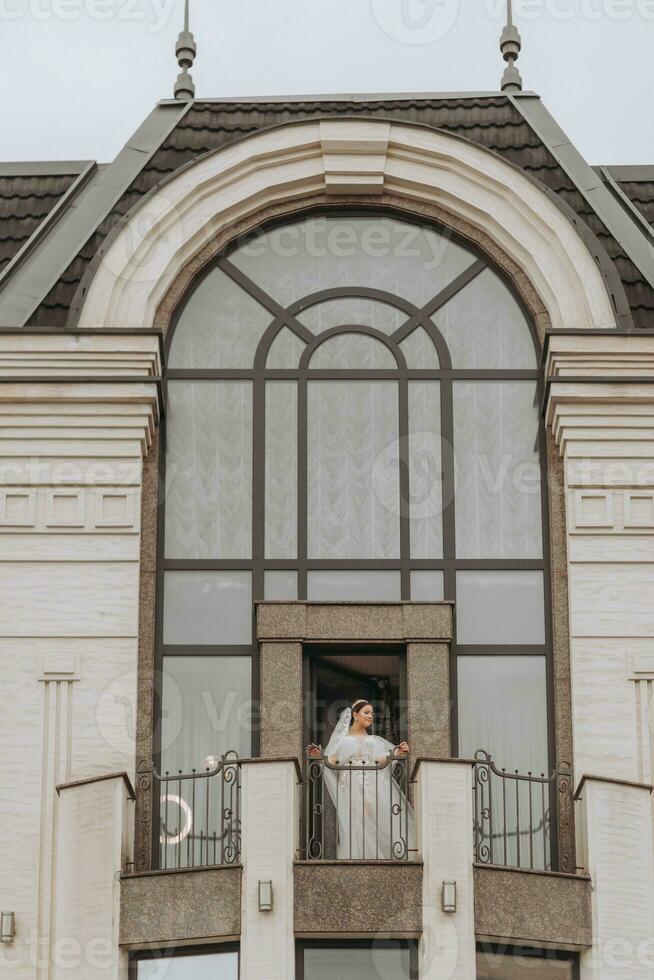 bride on the balcony of the hotel in a white robe with a veil, free space, vertical photo. On your wedding day photo