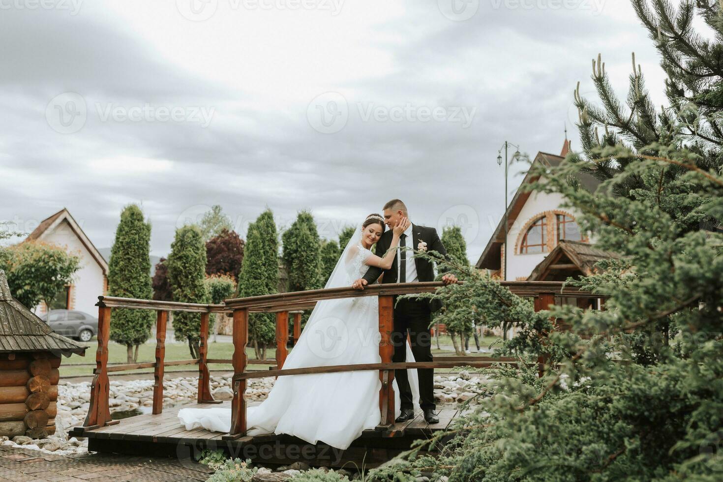 the bride and groom pose against the background of green trees. Wedding walk in nature in the park photo