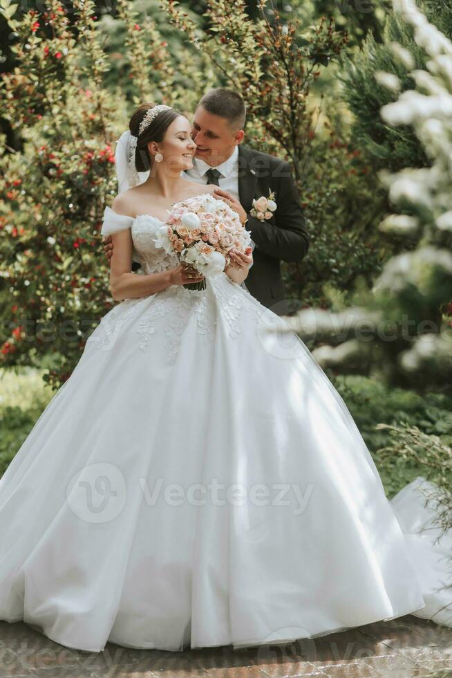 novio y novia besos en el parque. un Pareja de recién casados, el novia y acicalar, a un Boda en naturaleza, un verde bosque, besando, foto retrato. Boda Pareja