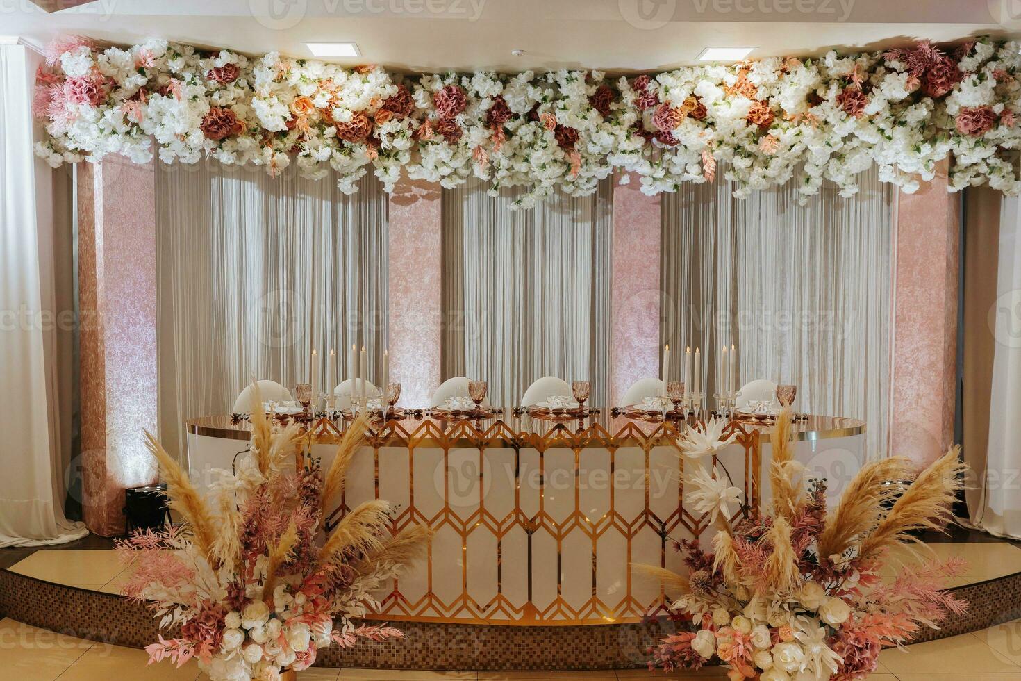Presidium of the bride and groom at the wedding. Everything is almost ready for the wedding celebration. A wedding banquet, many flowers, golden colors, a rich and refined wedding photo