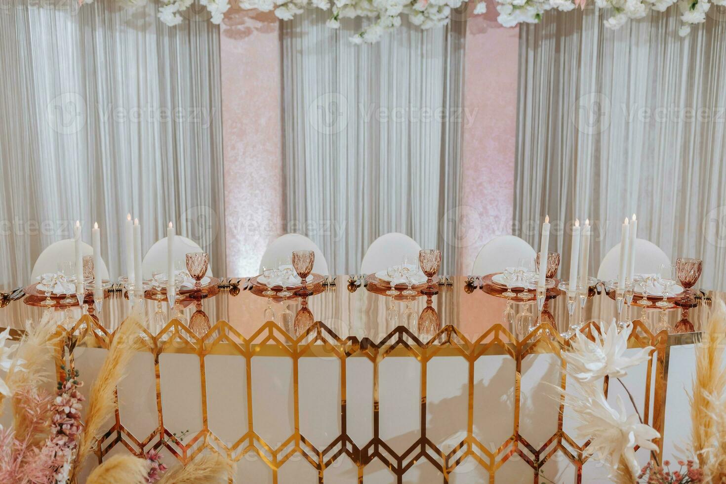 Presidium of the bride and groom at the wedding. Everything is almost ready for the wedding celebration. A wedding banquet, many flowers, golden colors, a rich and refined wedding photo
