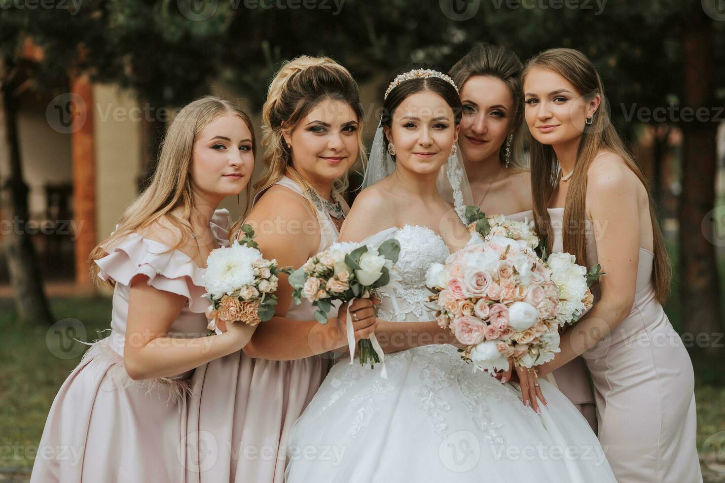 Group portrait of the bride and bridesmaids having fun. Wedding. A bride in a wedding dress and her friends in pink dresses on the wedding day. Stylish wedding in powder color. Concept of marriage. photo