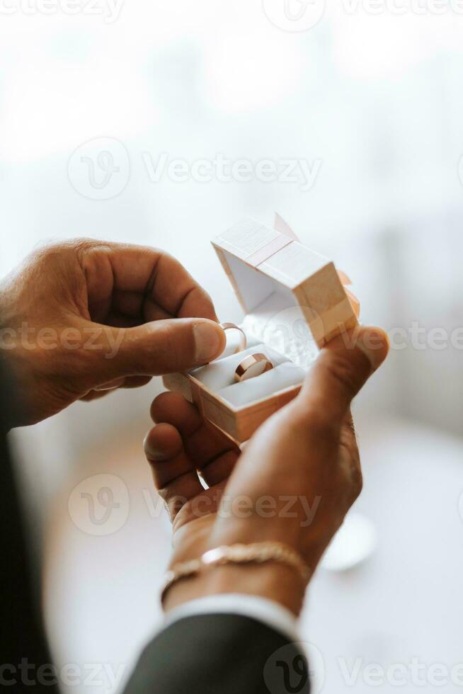 Gold wedding rings in a box in the hands of the groom close-up. photo