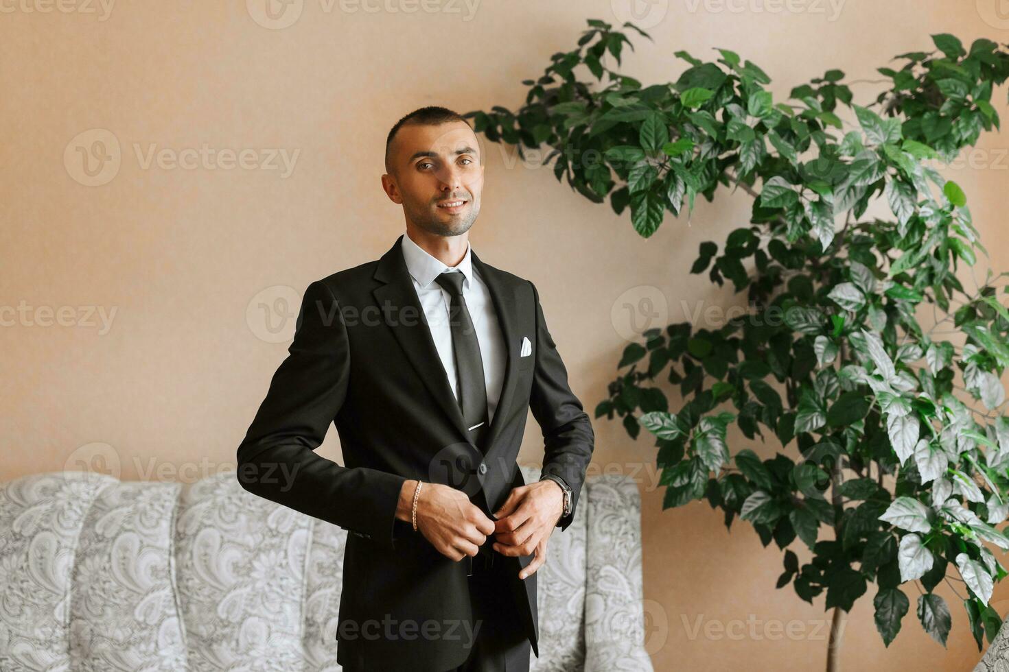 stylish man in a black classic suit with a tie. The groom is preparing for the wedding ceremony photo