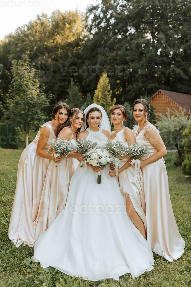 A group of beautiful women in matching dresses are smiling, celebrating, and having fun together. Friends of the bride in pink dresses celebrate the wedding together with the bride photo