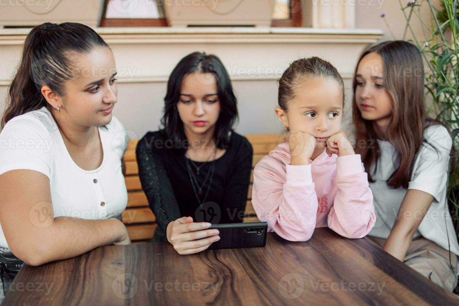 A child gets bored while adults or teenagers are busy or the concept of the effect of mobile phones on children's development, photo with selective soft focus