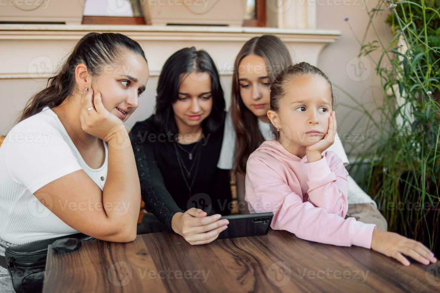 A child gets bored while adults or teenagers are busy or the concept of the effect of mobile phones on children's development, photo with selective soft focus