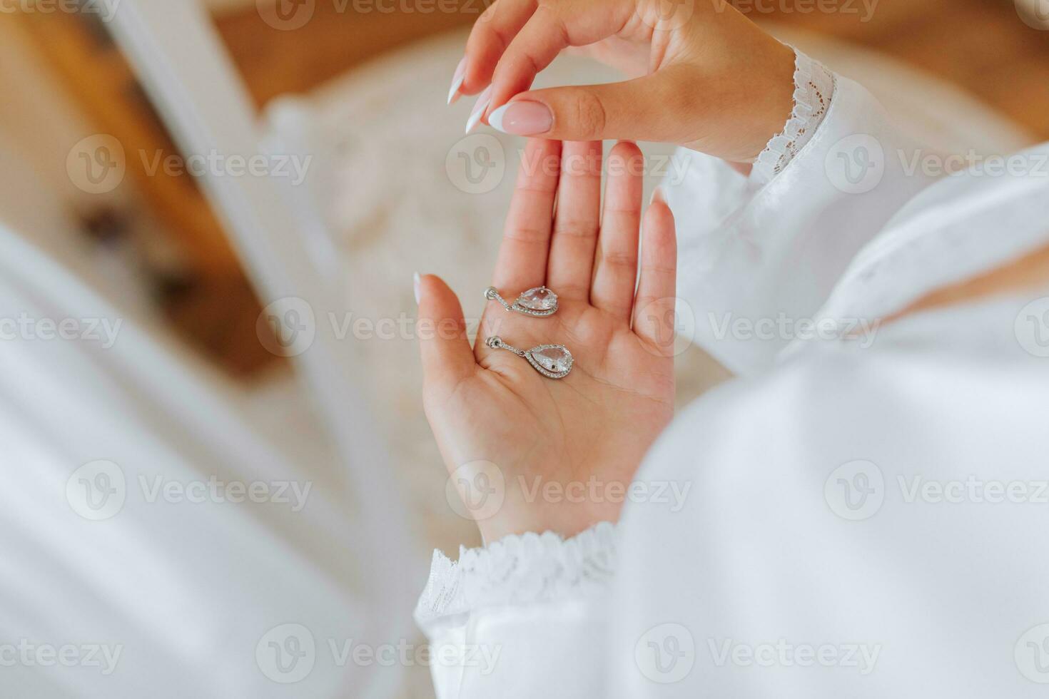 el novia sostiene en su manos y muestra su pendientes con precioso piedras, de cerca. Mañana de el novia. el Boda día. foto