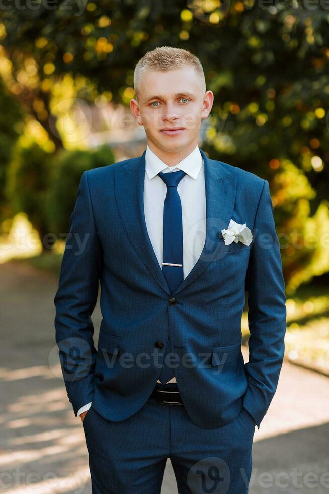 the groom in a blue suit and bow tie posing in the photo