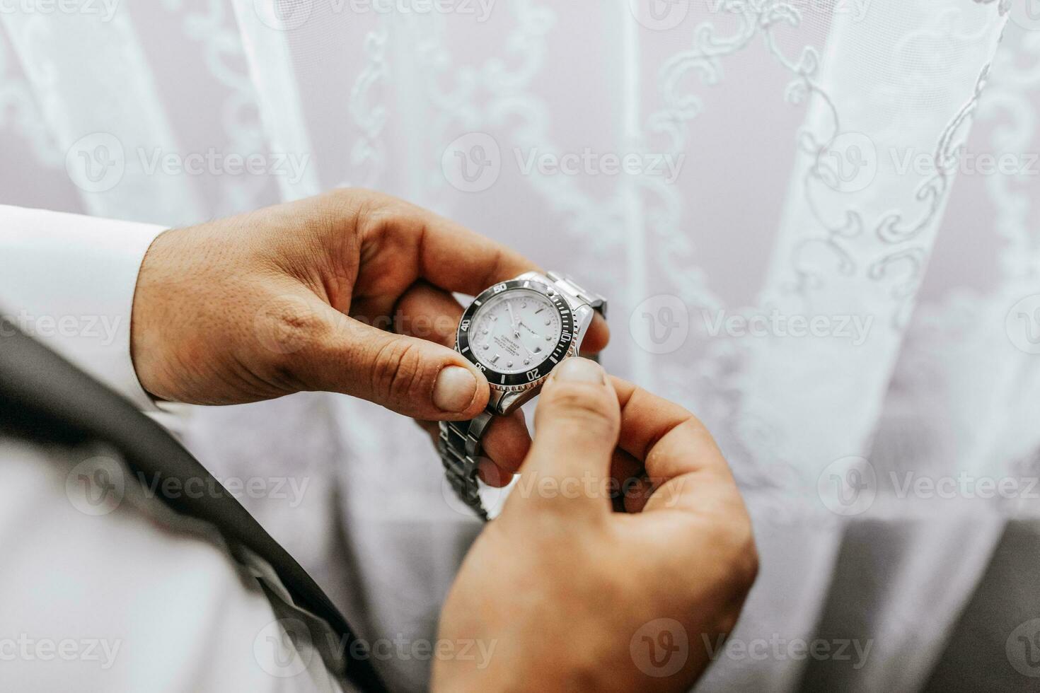 businessman dresses and adjusts his watch, preparing for a meeting. The groom is preparing for the wedding. The man wears a white shirt. Stylish groom photo