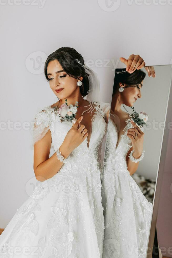 el novia sostiene un flor en el ojal en su manos. Boda flores un lujoso mujer es disfrutando su día. lujo Boda vestido. profesional maquillaje foto