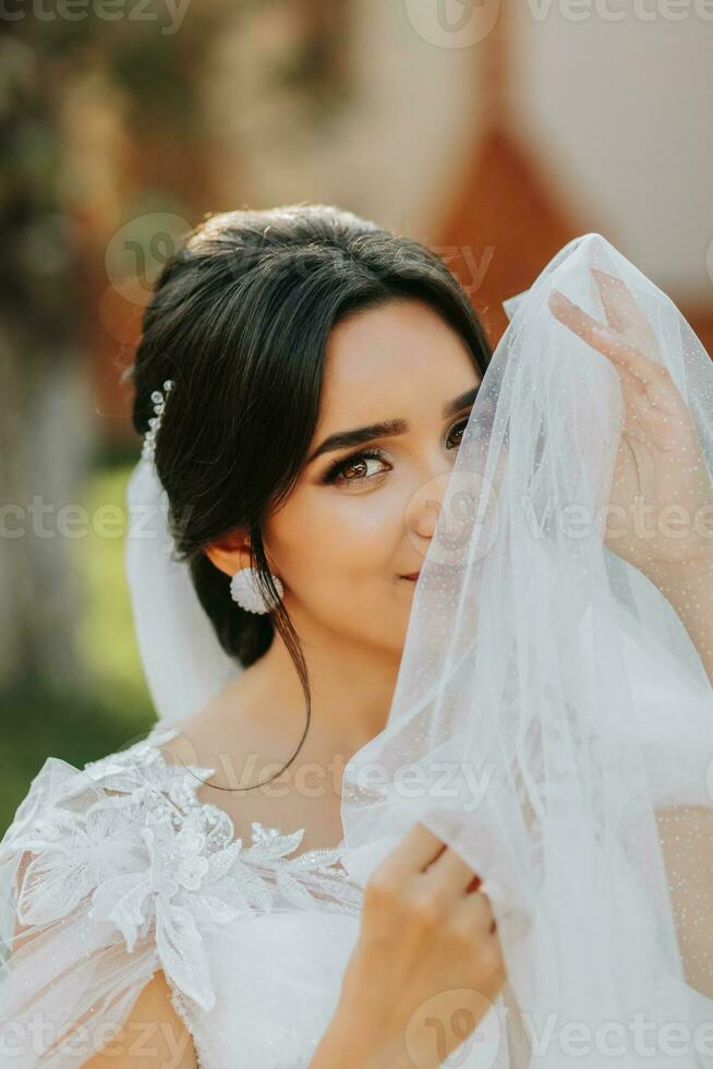 Beautiful bride in a fashionable wedding dress on a natural background in the park. A stunning young bride is incredibly happy. Happy girl on her wedding day photo
